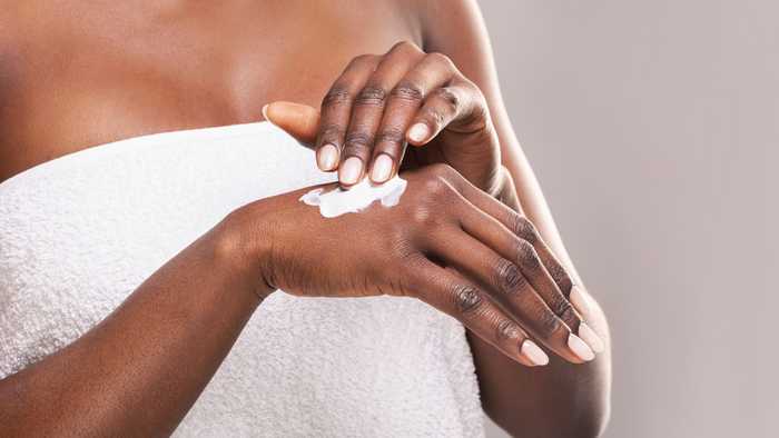 Woman in towel applying hand cream