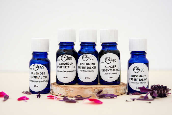 Oleo Bodycare Essential Oils set out on a table top surrounded by flower petals
