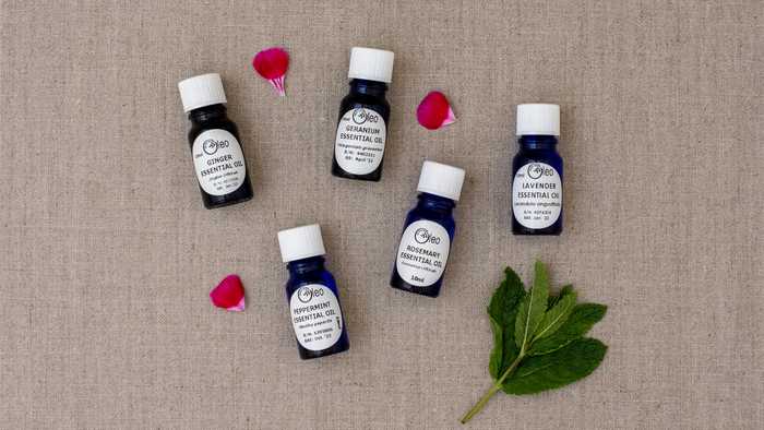 Essential Oils by Oleo Bodycare laid flat on a hessian surface with a sprig of mint and rose petals, symbolising the natural ingredients found in their products