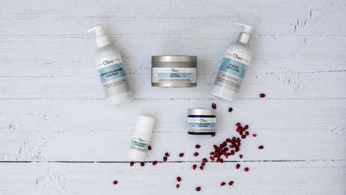 Natural, vegan skincare laid flat on a table with pomegranate seeds 