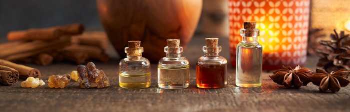 A selection of essential oils, cloves and cinnamon sticks in warm lightling