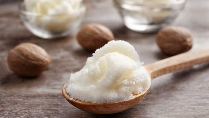 Shea butter on a spoon with shea nuts