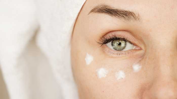 Lady apply moisturiser around her eye Lady apply moisturiser around her eye