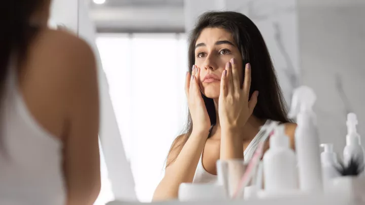Lady looking concerned at herself in the mirror