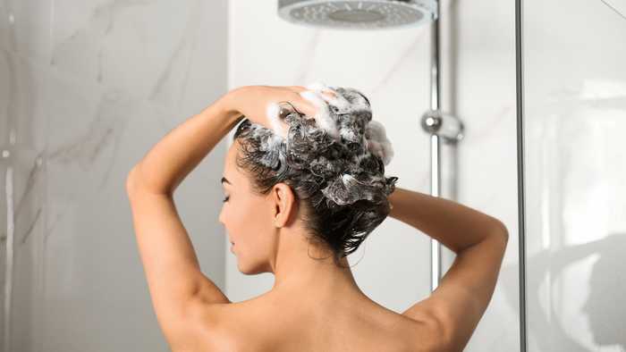 Lady washing her curly hair in the shower