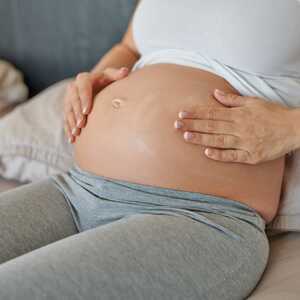 Lady applying body moisturiser to her tummy during pregnancy