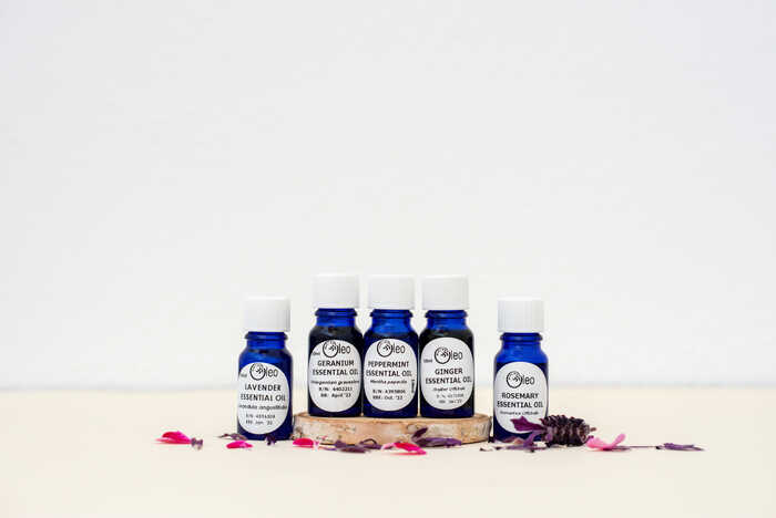 Oleo Bodycare Pure Essential Oils Oleo Bodycare Essential Oils set out on a table top surrounded by flower petals