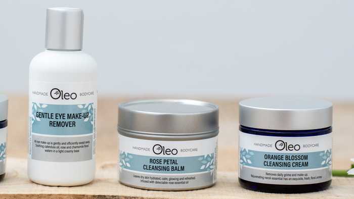 Oleo Bodycare handmade vegan skincare laid out on a wooden table in a bathroom