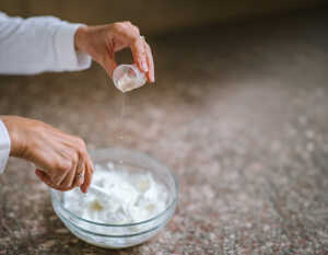 Olivia pouring carrier oils into a bowl of handmade moisturiser.