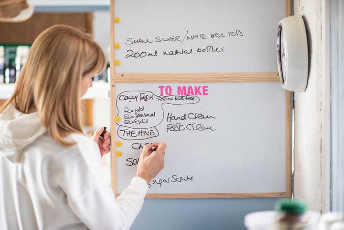"It is not about adding another thing to your to-do list." Oleo Bodycare founder writing on a whiteboard keeping on top the latest vegan skincare products she needs to make