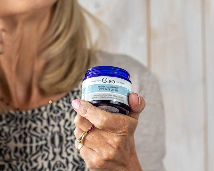 Olivia, Oleo Bodycare founder, holding and applying her new Protect and Hydrate SPF30 Face Cream