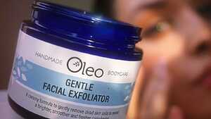 A smiling woman holds a fern among autumn leaves on a light background.